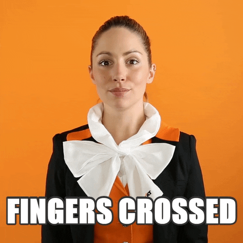 A woman raising both her arms and crossing both of her fingers simutaneously with 'fingers crossed' capitioned below.