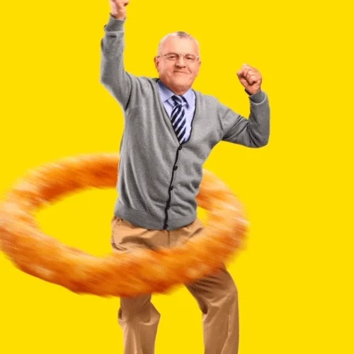 gray-haired older man with an excited facial expression swinging a giant onion ring around his waist hoola hoop style