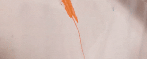 Person painting using a paintbrush and orange paint