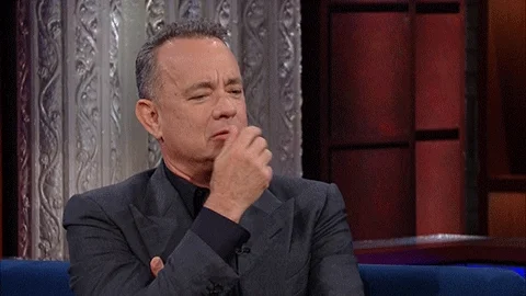 Tom Hanks looking to the side, putting his fingers on his face, thinking and looking confused
