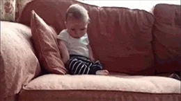Baby sleeping while sitting up on a couch and falls over.