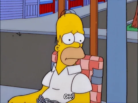 Homer Simpson sits in a chair looking shocked and upset. He says, 