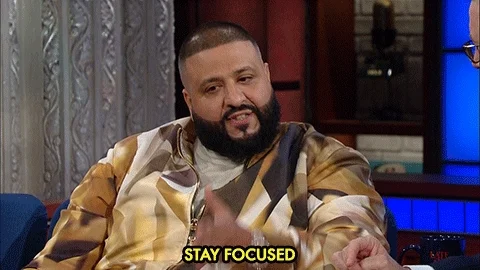 DJ Khaled sitting down during a talk show saying 'Stay Focused'