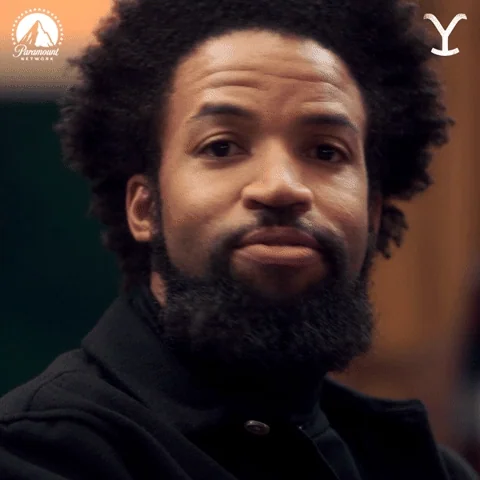 A man with an afro and beard gives a knowing look as he nods.