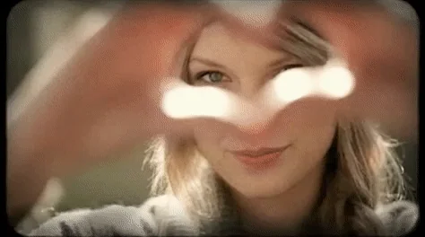 Taylor Swift making a heart with her hands.