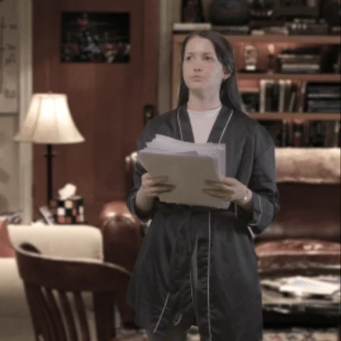 A woman throws papers in frustration, overwhelmed in a living room cluttered with notes.