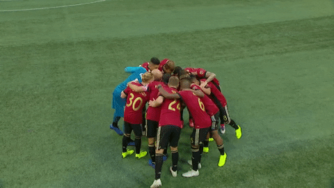 Soccer team huddling before a game and then running out on the field