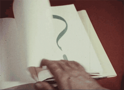 A person leafing through a book that has question marks on every page