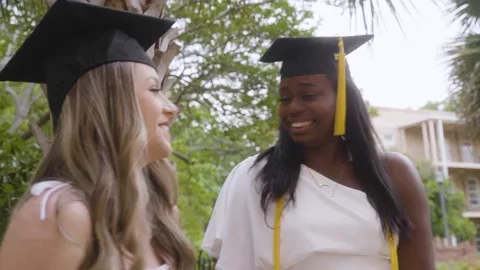 Two female graduates talking and laughing.
