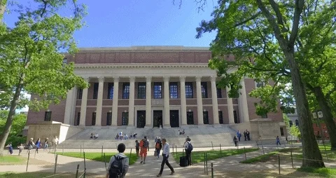 Students walking into a Harvard campus building as the camera pans backwards.