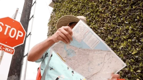 A middle-aged man who looks rather confused looking at a map in town.