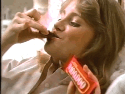 A woman eating a candy bar. The candy bar label reads 