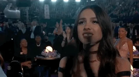 Olivia Rodrigo applauding at an awards show.