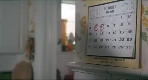 With a pen on her lips, a woman closely inspects the dates on a wall calendar.