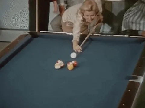 Old footage of two couples playing pool in a game room.
