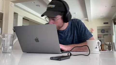 A man working in front of a laptop while drinking coffee in a home office.