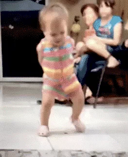A baby takes small steps and does a dance.