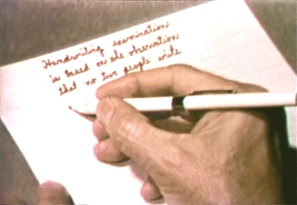 Old film footage of a man handwriting a letter.