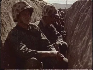 US soldiers in a trench watching a nuclear test.