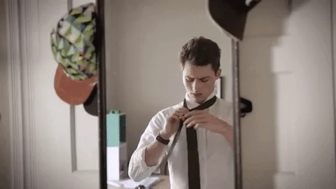 A young man adjusting his tie.