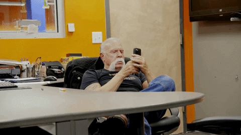 man sitting on a chair scrolling through his phone