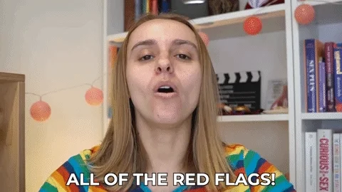 A white woman saying 'All of the red flags' while 8 small red flag illustrations appear around her.