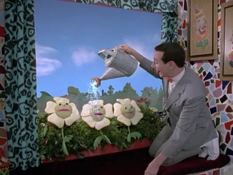 PeeWee Herman watering flowers.