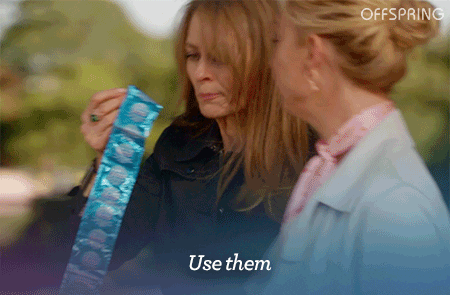 Lady handing another lady a strip of condoms.