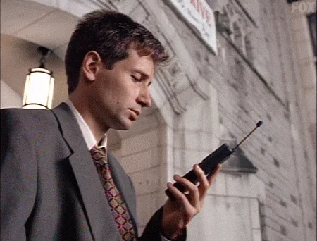 David Duchovny looking at an old mobile phone with message that reads 