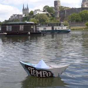 A paper boat floating on a river with a castle in background.