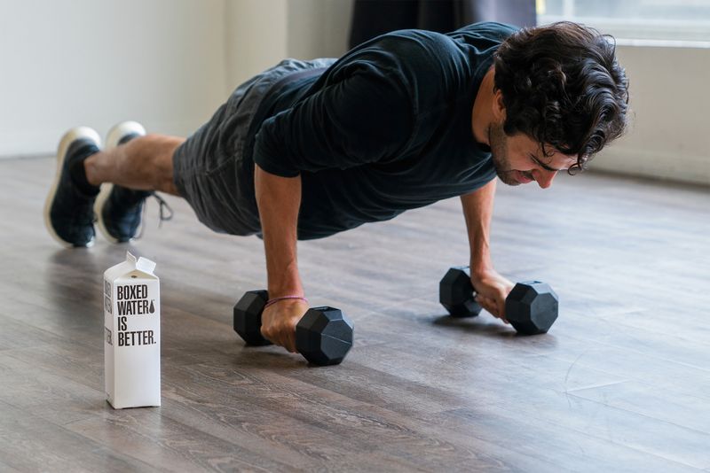 Man in a pushup with dumbbells in hands.