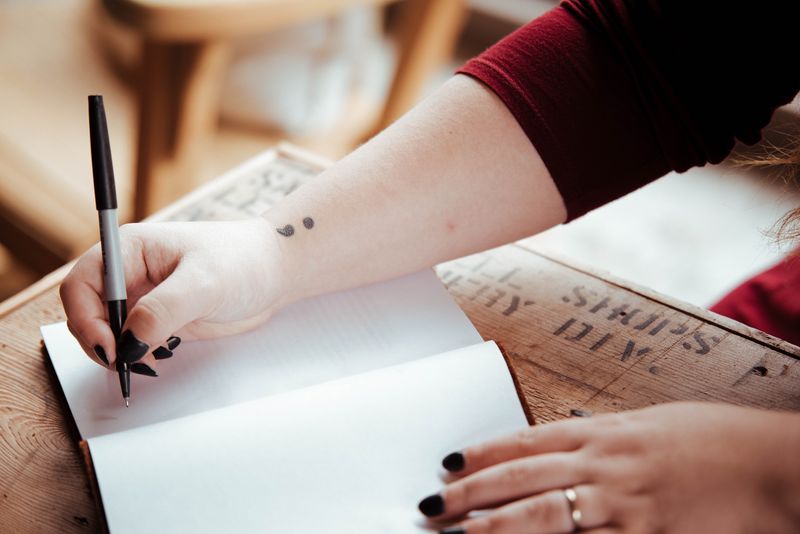 A person using a notebook and pen to sketch some logo design basics.