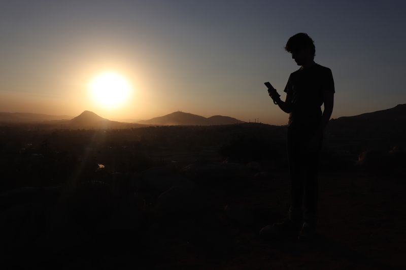 A person on a mountain looking at their phone.