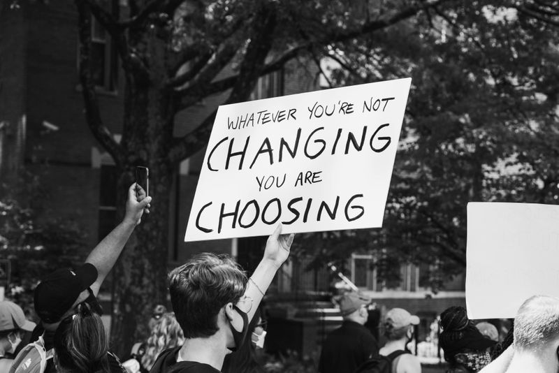 A sign at a protest that reads: whatever you're not changing, you're choosing.