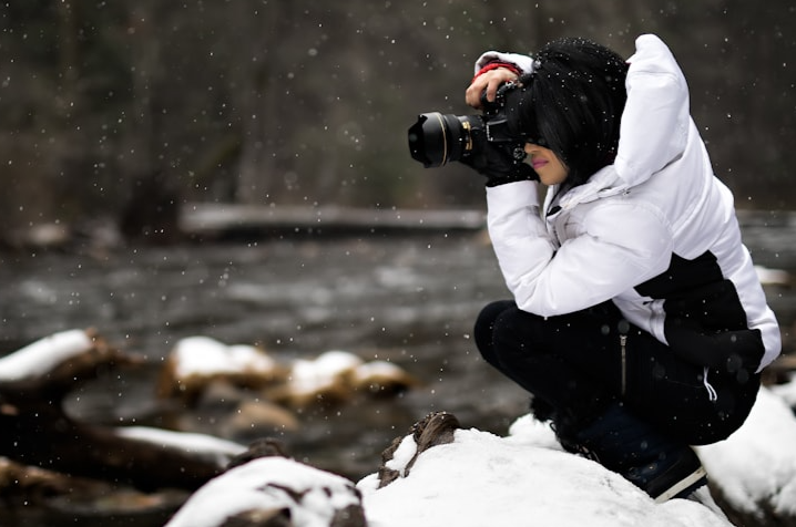 A person taking a photo on an icy river.