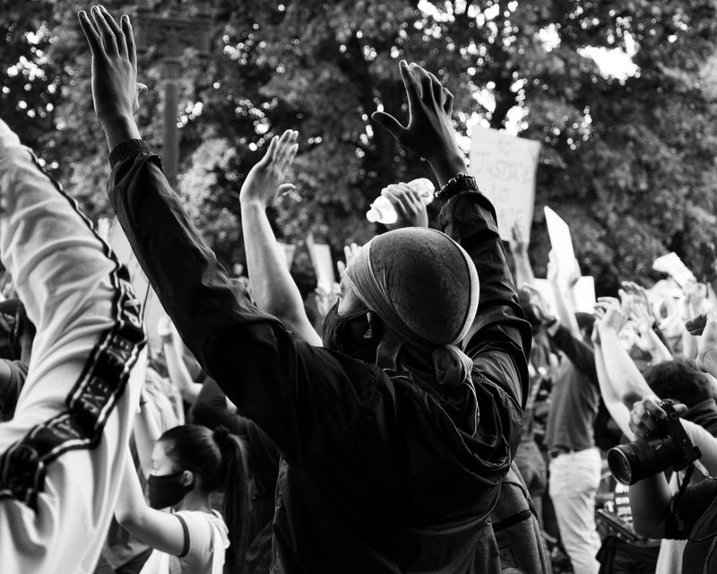 People at a protest with their hands raised.