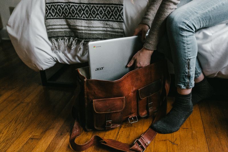 A person placing their laptop in their bag.