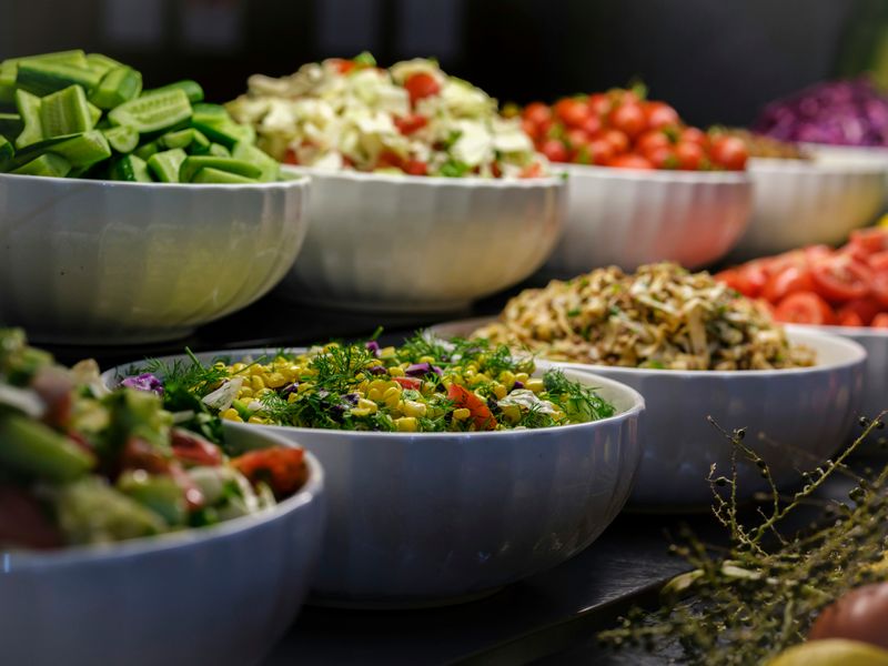 Different plant-based foods in white bowls lined up for serving.