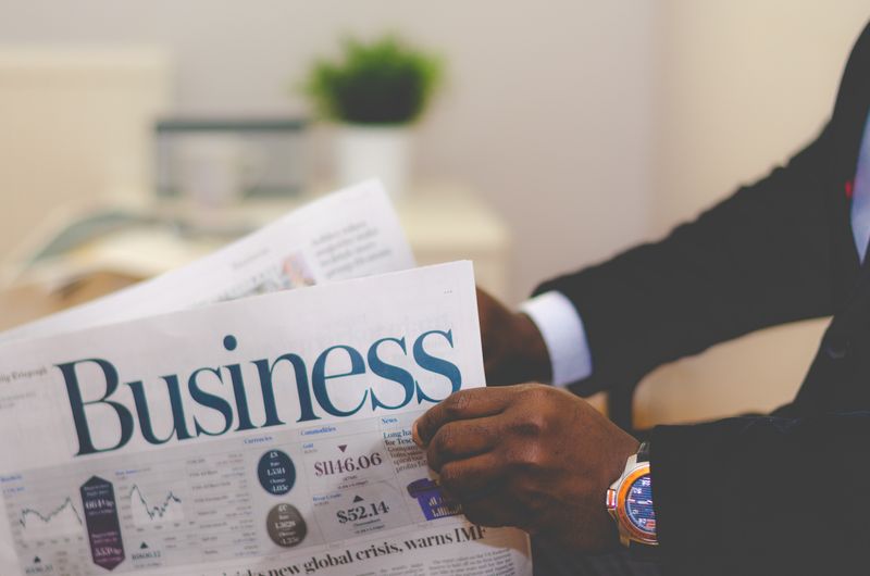 A Black businessman reading the business section of a newspaper.