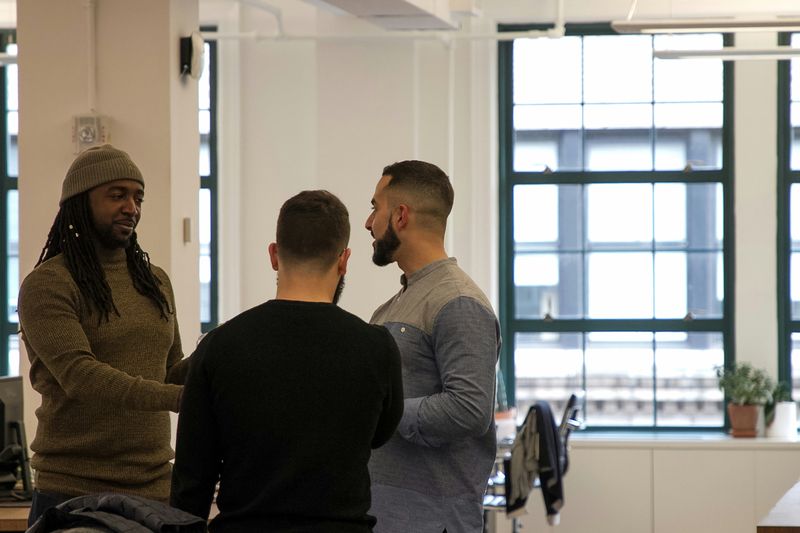 Three men greet each other in an office.