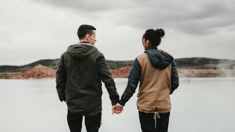 Two people walking side by side, holding hands.