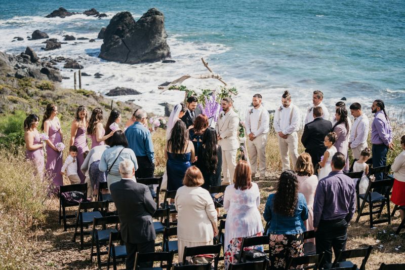 A destination wedding ceremony by the beach, overlooking the water.