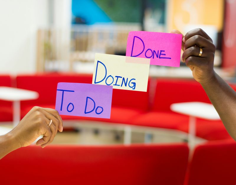 Hands holding Post It notes that say "To Do, Doing, Done".