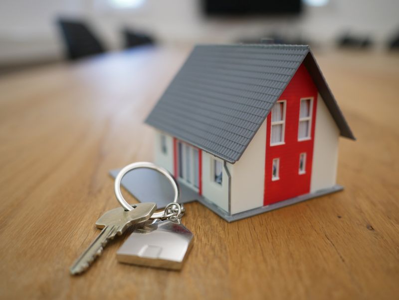 Small home figurine with a key on a metal house keychain. 