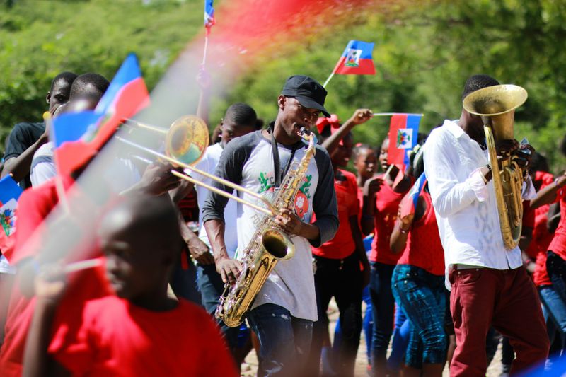 A group of people playing instruments and waving the Haitian flag.