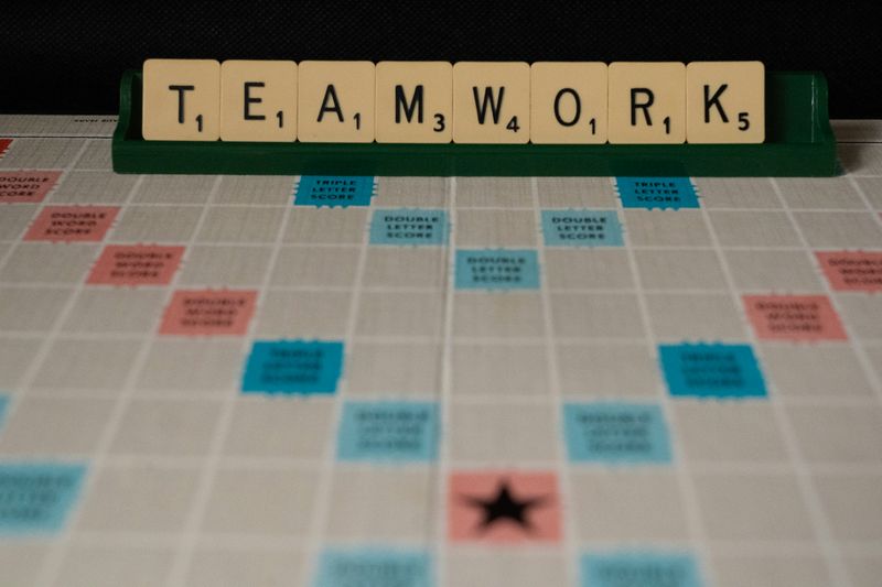 Teamwork is spelled using Scrabble letters and shown on a Scrabble board.