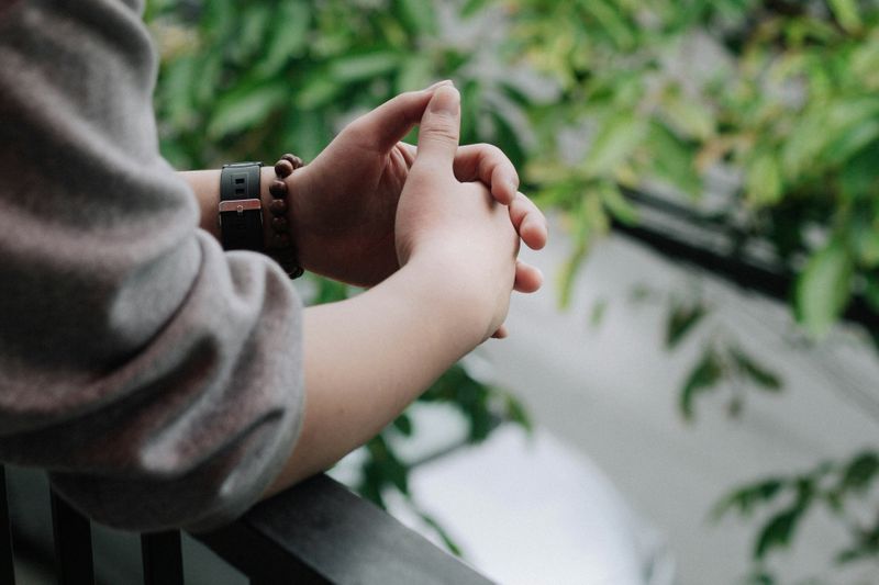 A close up shot of a person's hands interlocked over a balcony. 