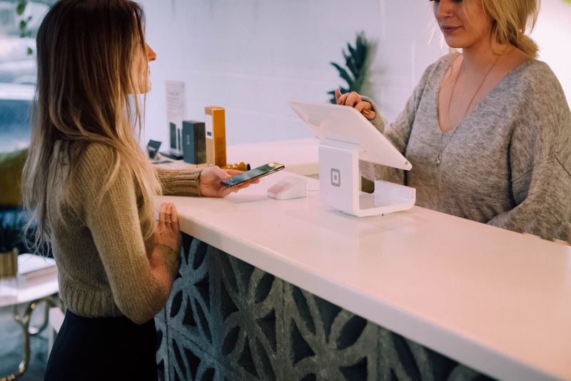 Woman paying at counter, another woman is operating point of sale device