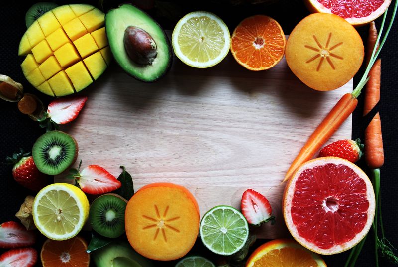 Cutting board surrounded by freshly cut fruit and vegetables