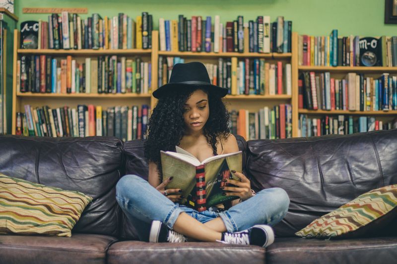 A woman sitting on a couch, reading a book. 